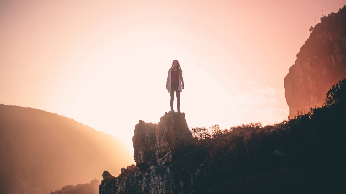 man standing on rock formation during sunset