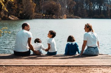 A family of five relaxing by a serene lake in Lyon, France on a sunny day.