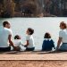 A family of five relaxing by a serene lake in Lyon, France on a sunny day.